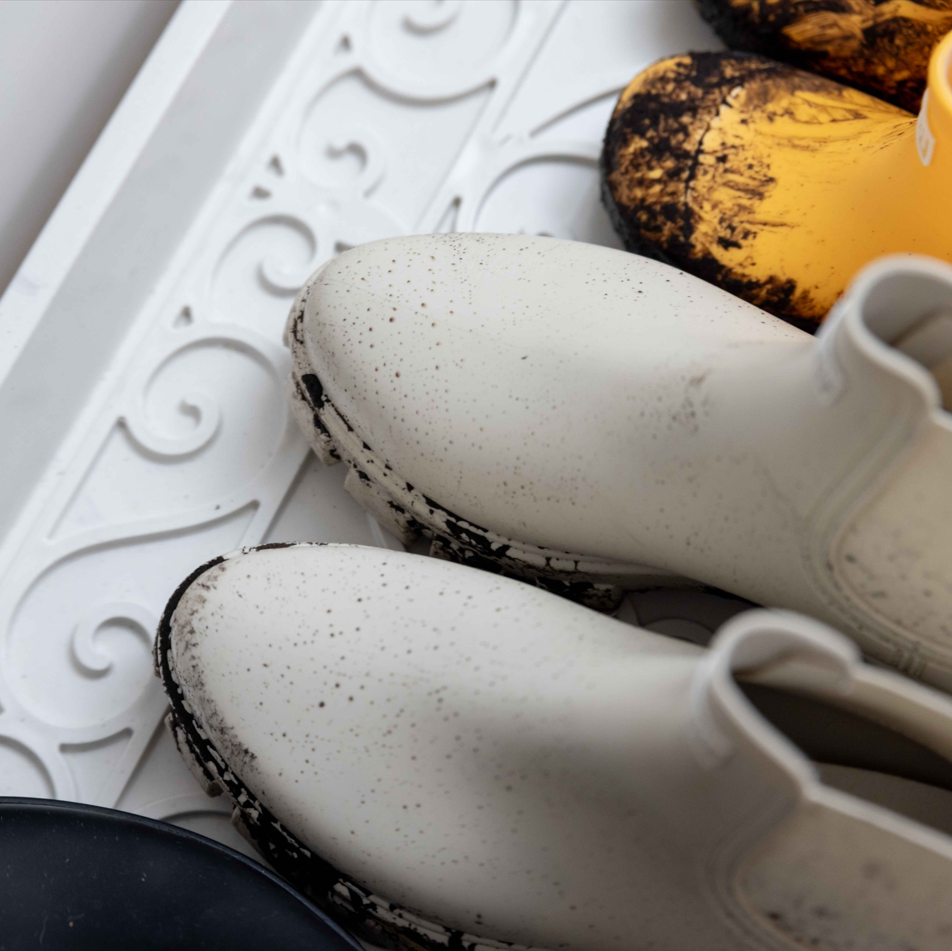 Rain boots and muddy shoes on a durable boot tray