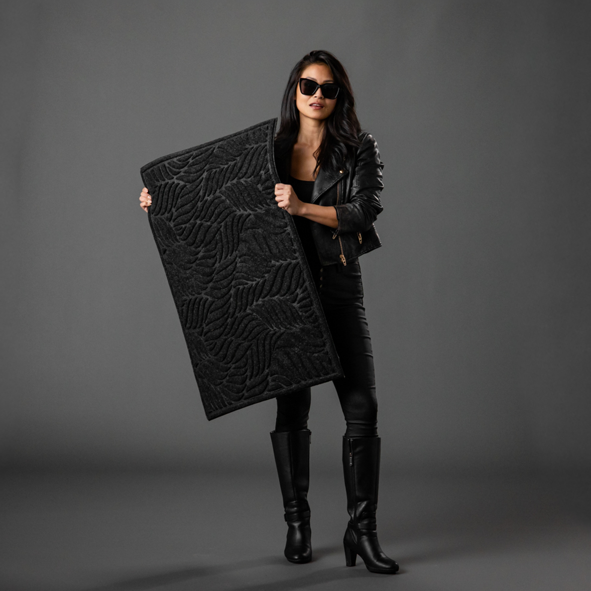 Woman holding a black leaf inspired door mat